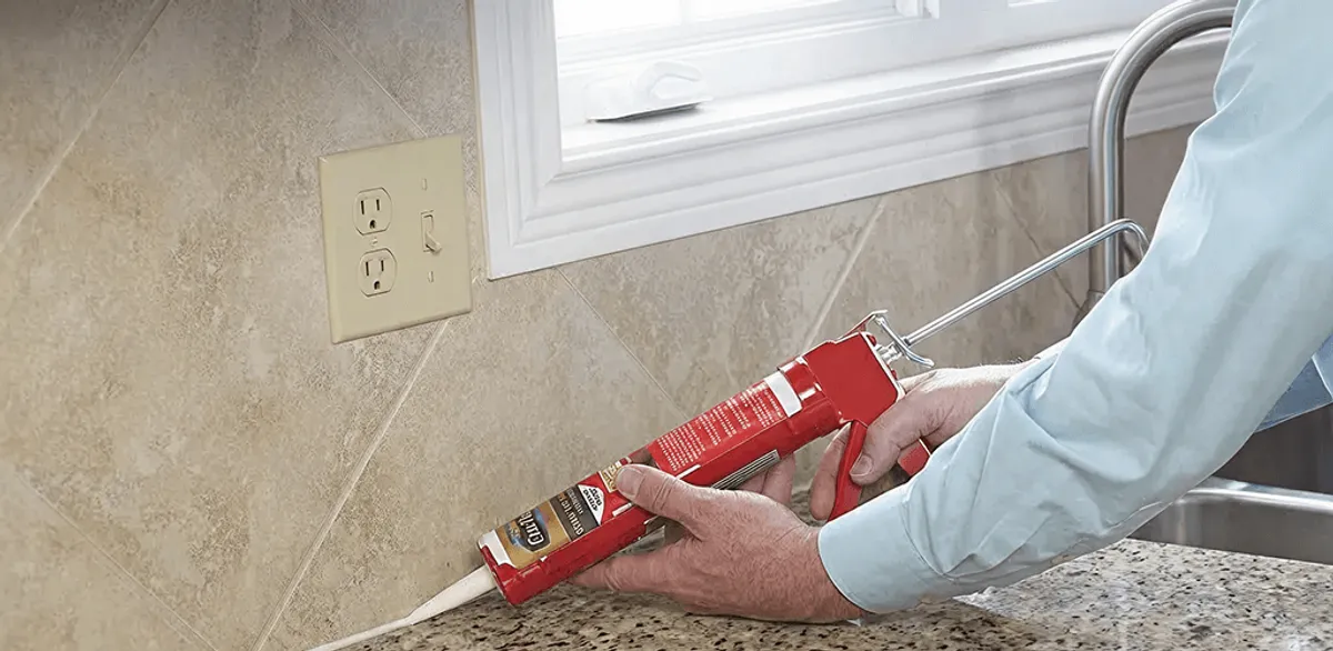 Handyman applying caulk along a kitchen backsplash and countertop seam in Sarasota, FL