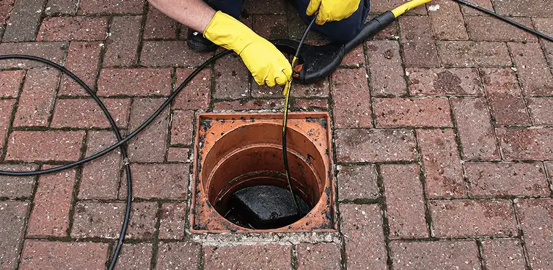 Drain cleaning technician using a drain snake to clear a clogged drain in Sarasota, FL
