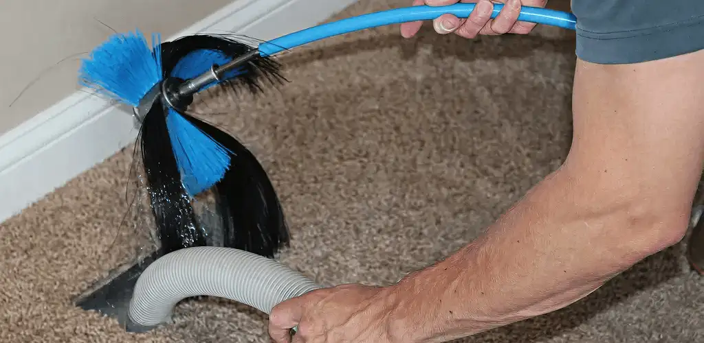 Dryer vent cleaning technician brushing lint from a vent line in Sarasota, FL