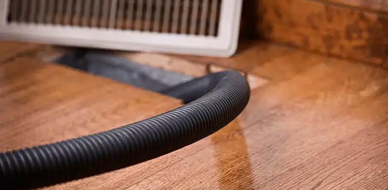 Air duct cleaning hose inserted into a floor vent for ductwork cleaning in Sarasota, FL