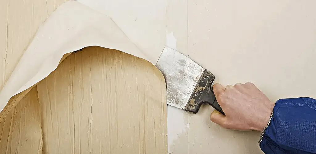 Handyman removing wallpaper with a scraper for wall preparation in Sarasota, FL