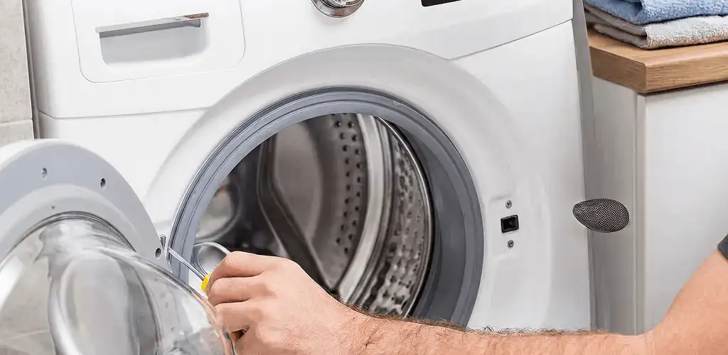 Handyman repairing a front-load washing machine and inspecting the drum in Sarasota, FL
