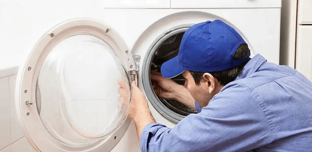 Washing machine repair handyman inspecting a front-load washer drum in Sarasota, FL