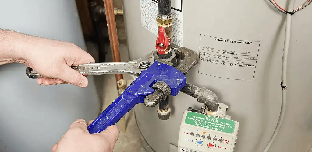 Water heater repair technician tightening the shutoff valve and supply line in Sarasota, FL